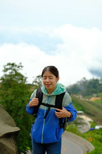 Portrait of young woman standing against sky