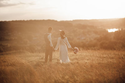 Couple kissing on field against sky