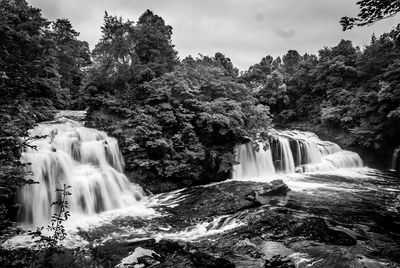 Scenic view of waterfall against trees