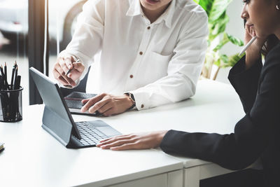 Midsection of woman using mobile phone while sitting on table