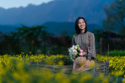 Portrait of a smiling young woman standing against plants