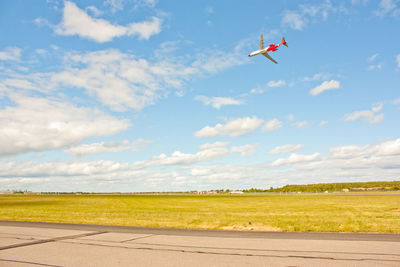 Airplane flying over field against sky