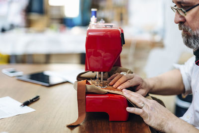 Focused male sewing material pieces on machine