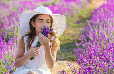 Cute girl smelling flowers sitting at farm