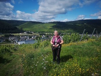 Portrait of smiling woman standing on land against sky