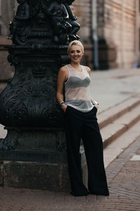 Portrait of young woman standing against building