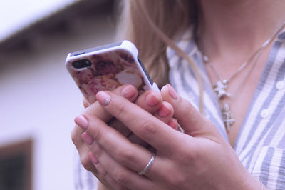 Midsection of woman using phone while standing outdoors