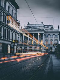 Light trail on street against buildings in city at twilight
