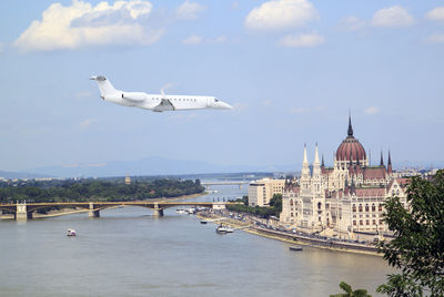 Airplane flying over river with city in background