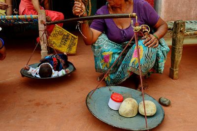 Low section of senior woman measuring baby girl on weight scale