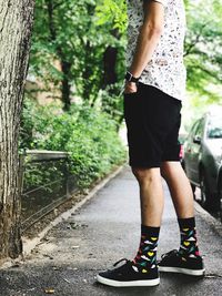 Low section of man standing on wet footpath