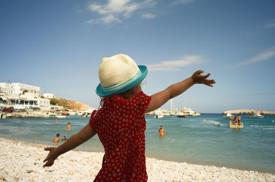 Full length of child on beach against sky with arms raised