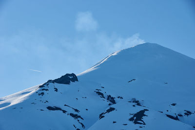 Low angle view of snowcapped mountains against blue sky