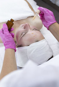 High angle view of doctor examining patient lying on bed at home