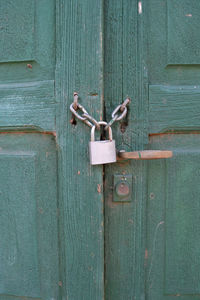 Close-up of padlocks on green wooden door