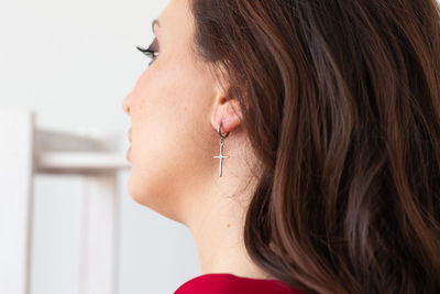 Side view of young woman holding heart shape against wall