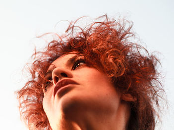 Low angle view of thoughtful woman looking away against sky