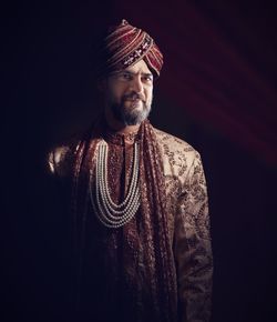 Portrait of man wearing traditional clothing against black background