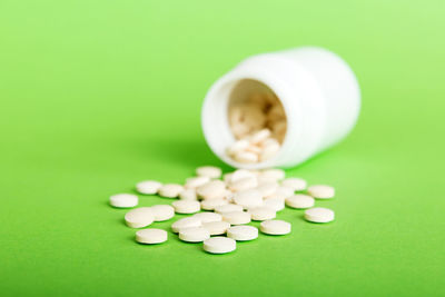 Pills spilling from bottle against pink background