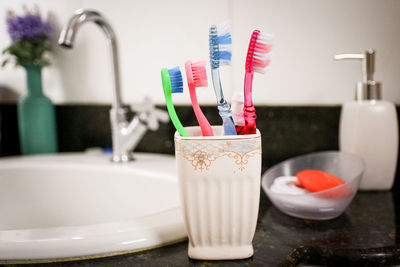 Close-up of family toothbrushes in glass at bathroom