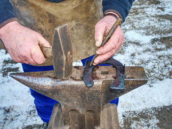 Midsection of man working on metal