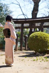 Woman in traditional clothing standing against plants