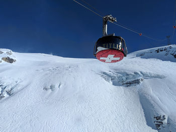 Overhead cable car over snow covered mountains against sky