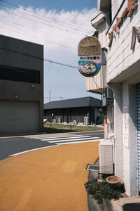 Road by buildings in city against sky