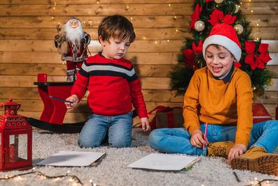 Children writing the letter to the three kings  with a christmas tree on a wooden background