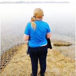 Rear view of young woman standing against sea