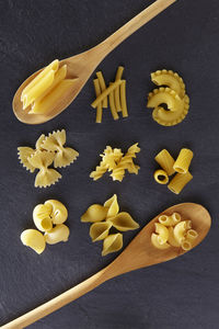 Various pasta in wooden spoons on slate