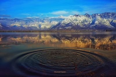 Scenic view of lake and mountains against blue sky