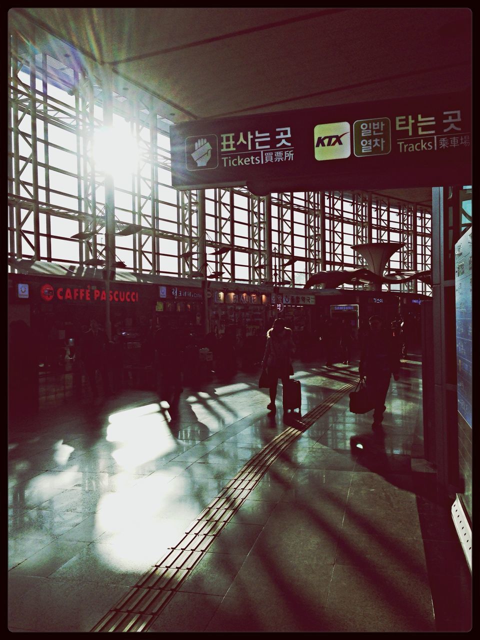 indoors, transfer print, auto post production filter, architecture, transportation, built structure, railroad station, public transportation, reflection, men, railroad station platform, tiled floor, illuminated, sunlight, lifestyles, travel, person, incidental people, mode of transport