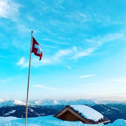 Red flag on snowcapped mountain against sky