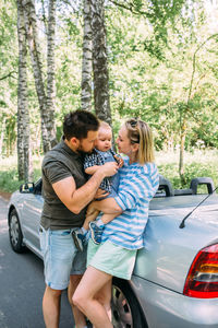 Mom, dad and little son in a convertible car. summer family road trip to nature