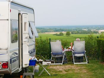 Rear view of people sitting on chair by van against clear sky