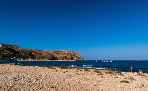 Scenic view of beach against clear blue sky