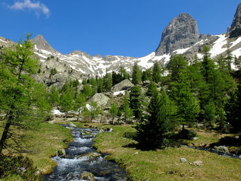 Scenic view of stream by mountains against sky