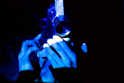 Close-up of hand holding cigarette against black background