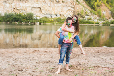 Full length of smiling young woman standing by lake