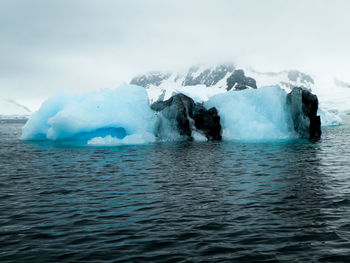 Sea and iceberg against mountain in antarctica