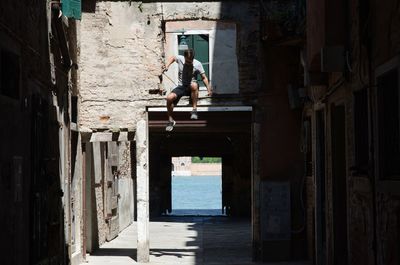 Full length of man jumping from old built structure in old town