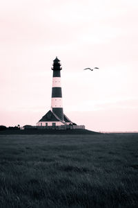 Lighthouse on field against sky
