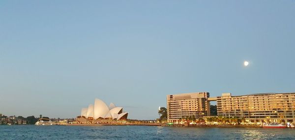 Sea by buildings against clear sky