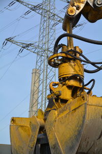 Close-up of construction machine with electricity pylon in background