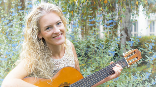 Portrait of a smiling young woman playing guitar