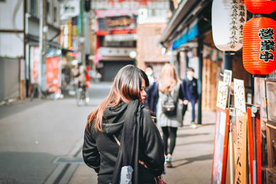 Rear view of woman standing on street in city