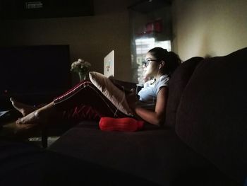 Side view of woman sitting on sofa at home