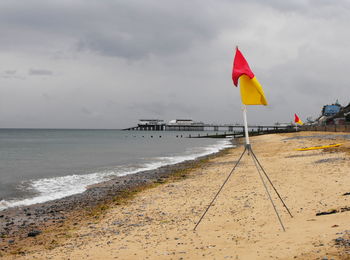 Scenic view of beach with flags against sky
