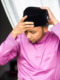 Close-up portrait of young man covering face with hand